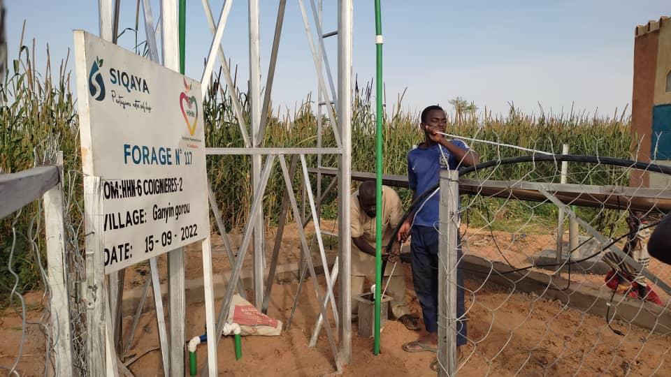 Installation d'un forage d'eau potable SIQAYA avec signalisation du projet au village.