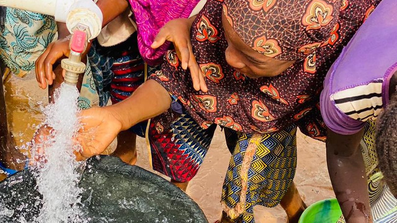 Femmes remplissant des seaux à la pompe